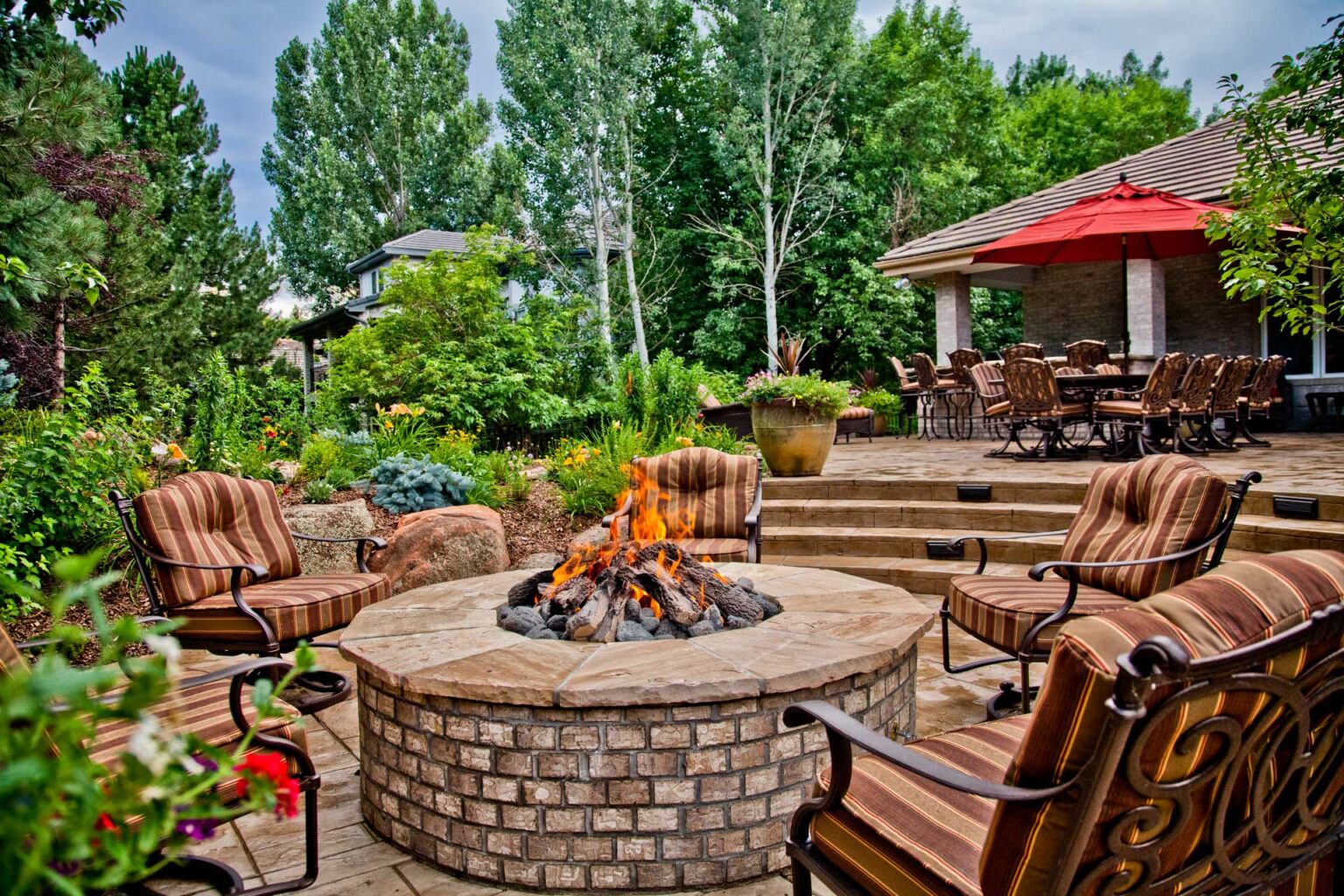 Custom stone patio with built-in fire pit surrounded by comfortable seating